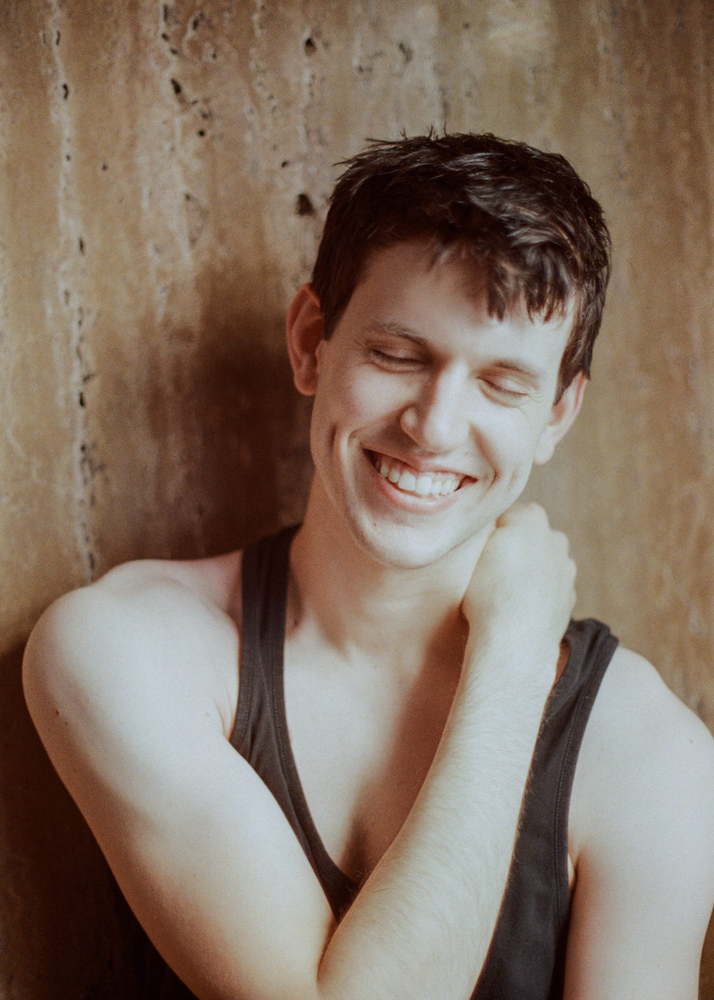 A man in a black tank top smiling.